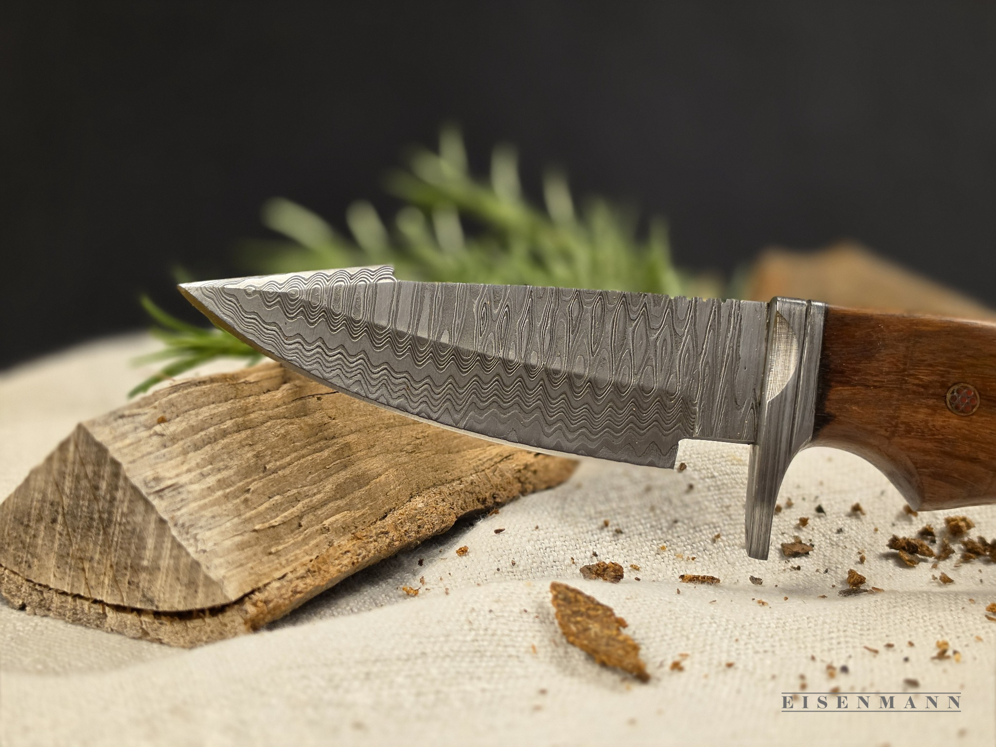 Jagdmesser mit Damastklinge und Holzgriff auf einer Holzoberfläche