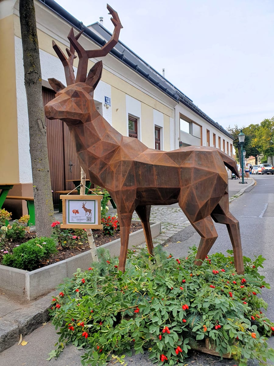 Hirsch aus facettiertem Stahl mit rostbrauner Oberfläche in Lebensgröße am Straßenrand