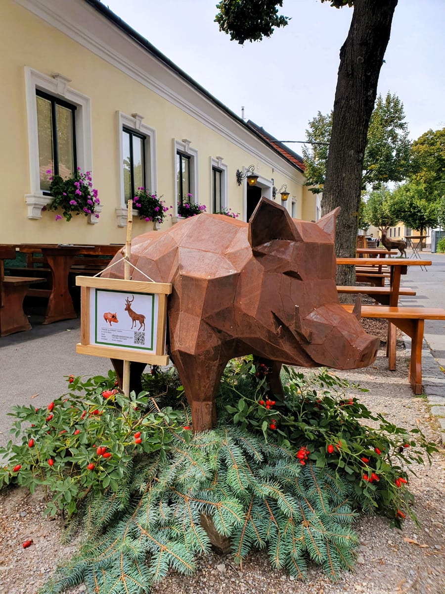 Wildschwein aus facettiertem Stahl mit rostbrauner Oberfläche vor einem Gasthaus